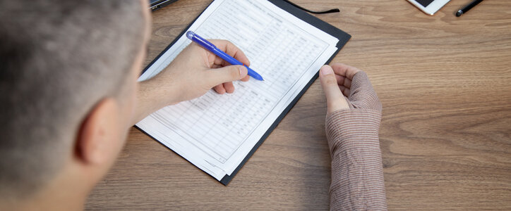 Disabled man with bandaged arm signing document, work accidents